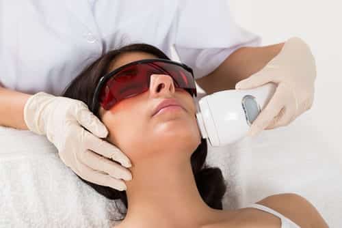 A woman getting a laser resurfacing procedure by an aesthetician.