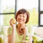 happy middle aged woman smiling and holding an apple