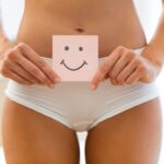 woman in white bikini holding smiley notepadenstrual cup on pink background