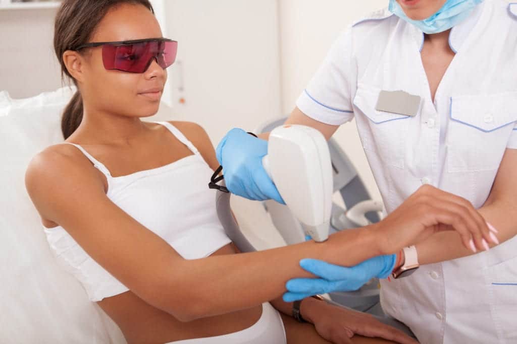 Lovely African woman getting laser hair removal on her arms at beauty salon