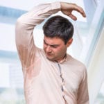 Man with hyperhidrosis sweating under armpit in office
