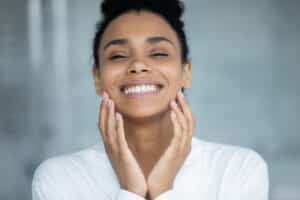 Beautiful woman smiling with her hands on her face revealing refreshed, even skin for fall from laser resurfacing