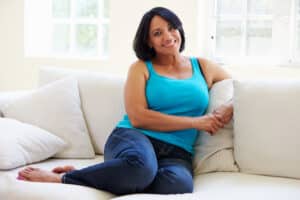 Woman in her 50s sits comfortable on the couch.
