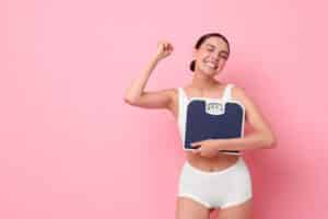 Woman holding scale celebrating weight loss with HCG Therapy in Brownwood, TX