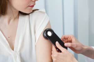 Dermatologist examines birthmarks on patient's arm after skin cancer