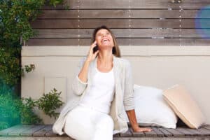 Happy woman in her 50s smiles while talking on the phone, confident in her body