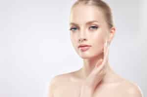 Beautiful blonde woman with clear complexion admires her own skin